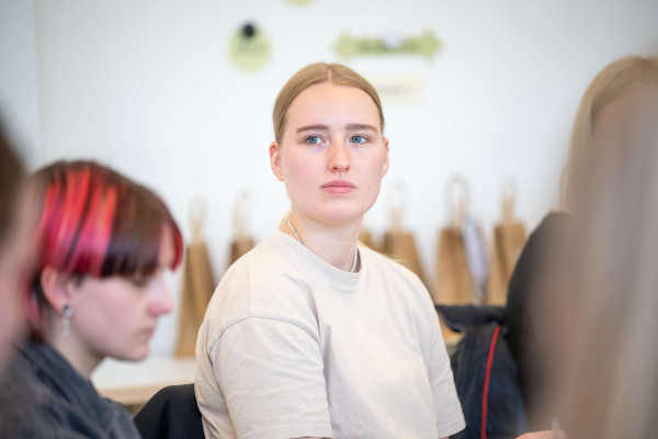 Junge Frau hört in einer Seminarrunde aufmerksam zu