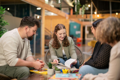 Menschen sitzen in gemütlicher Runde zusammen und arbeiten mit Karten und Materialien